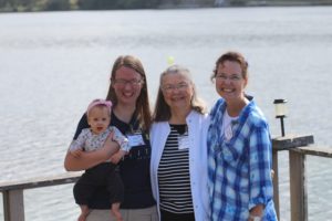 Three women and a baby in front of a lake