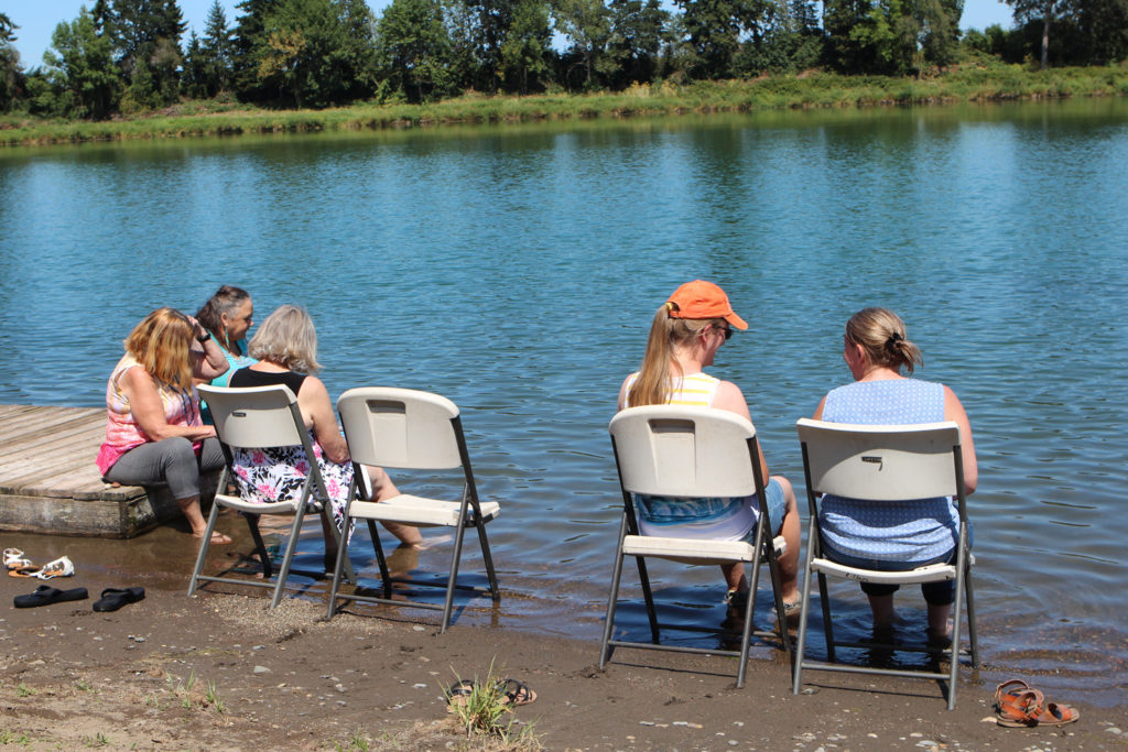 ladies seated in chairs at the edge of the lake with feet in the water